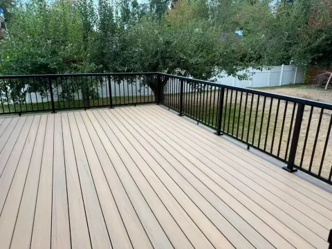 Tan composite deck with black railing overlooking the yard