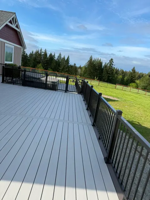 Long gray composite deck with black railing and forest view