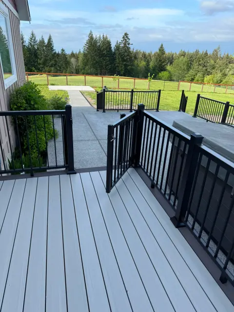 Gray deck connecting to a concrete path and black gate