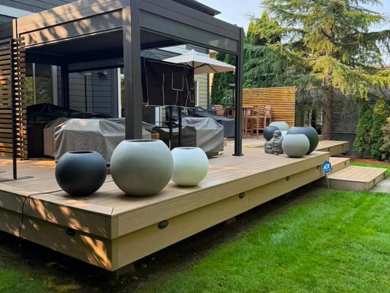 Composite deck with a black pergola and planters in a Seattle backyard